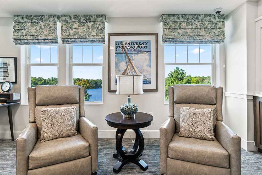 A cozy living room with two comfortable chairs flanking a stylish coffee table, set in front of large windows offering a scenic view.