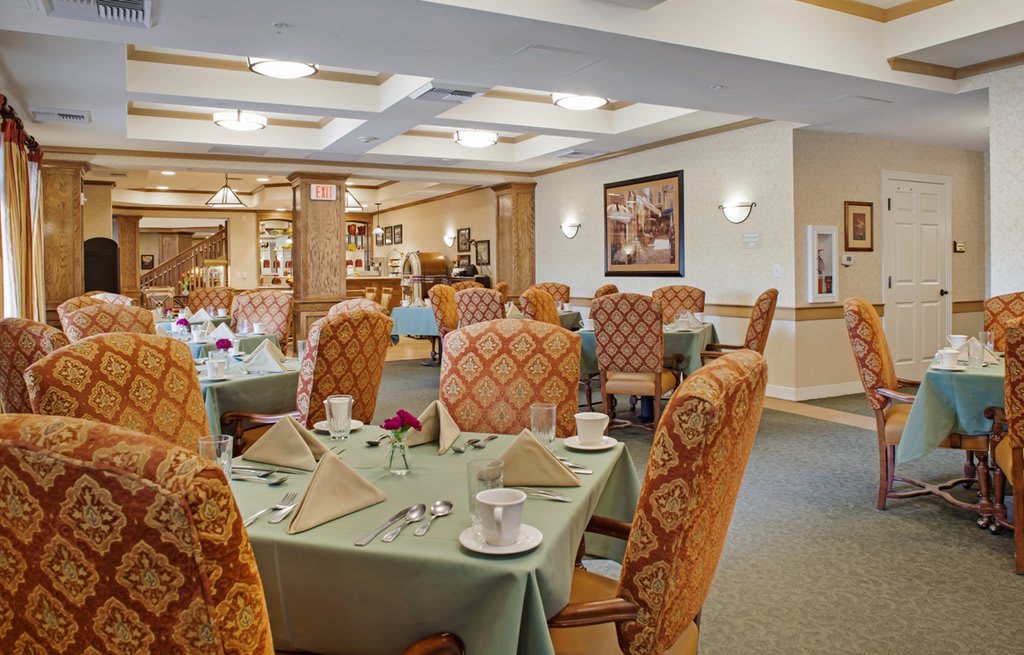 A cozy dining room with neatly set tables and upholstered chairs.