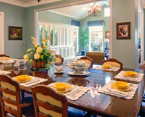 An elegantly decorated dining room with a beautifully set table and natural lighting.