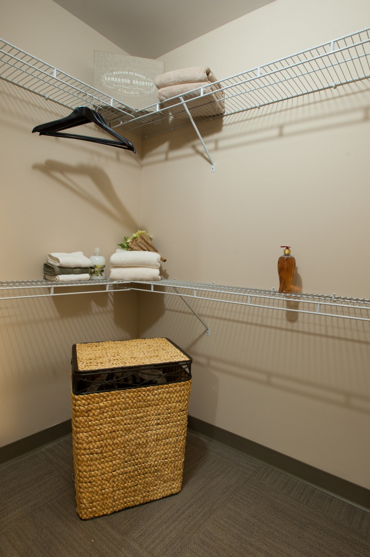 An empty closet with wire shelving, some hangers, folded towels, and a woven basket.