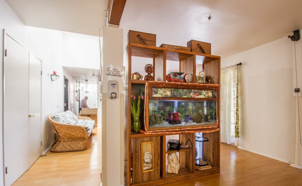 A cozy living room featuring a wooden shelf with an aquarium centerpiece and various decorative items.