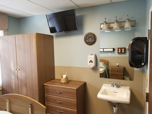 A well-furnished hospital room featuring a television, wash basin, and decorative elements.