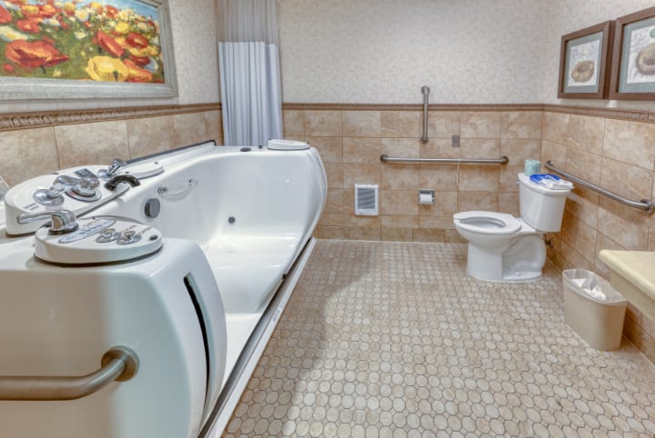 A modern, accessible bathroom with a large bathtub and tiled flooring.