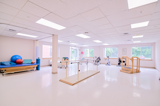 A spacious physical therapy room designed for rehabilitation, featuring exercise equipment and natural light.