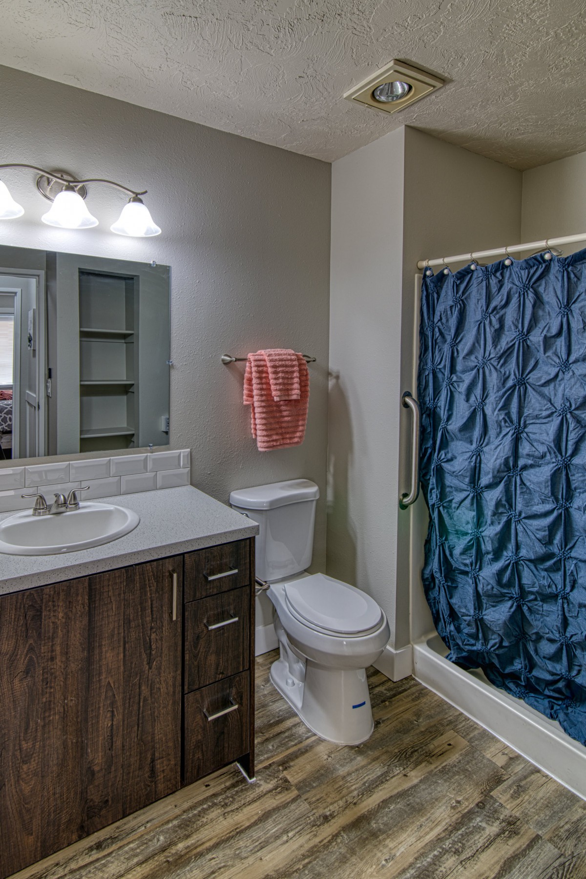 A modern bathroom with a sink, toilet, and shower featuring a blue curtain.