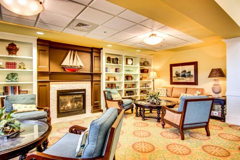 A cozy living room with a fireplace and bookshelves, featuring comfortable furniture and warm lighting.