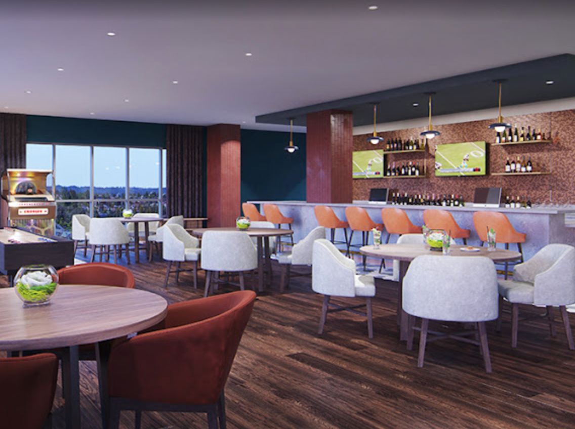 A modern restaurant interior featuring a dining area with a bar, stylish chairs, and tables.
