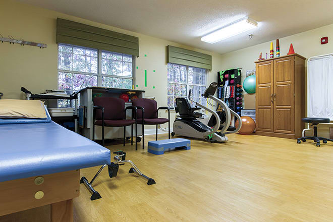 A rehabilitation exercise room with fitness equipment and therapy tools.