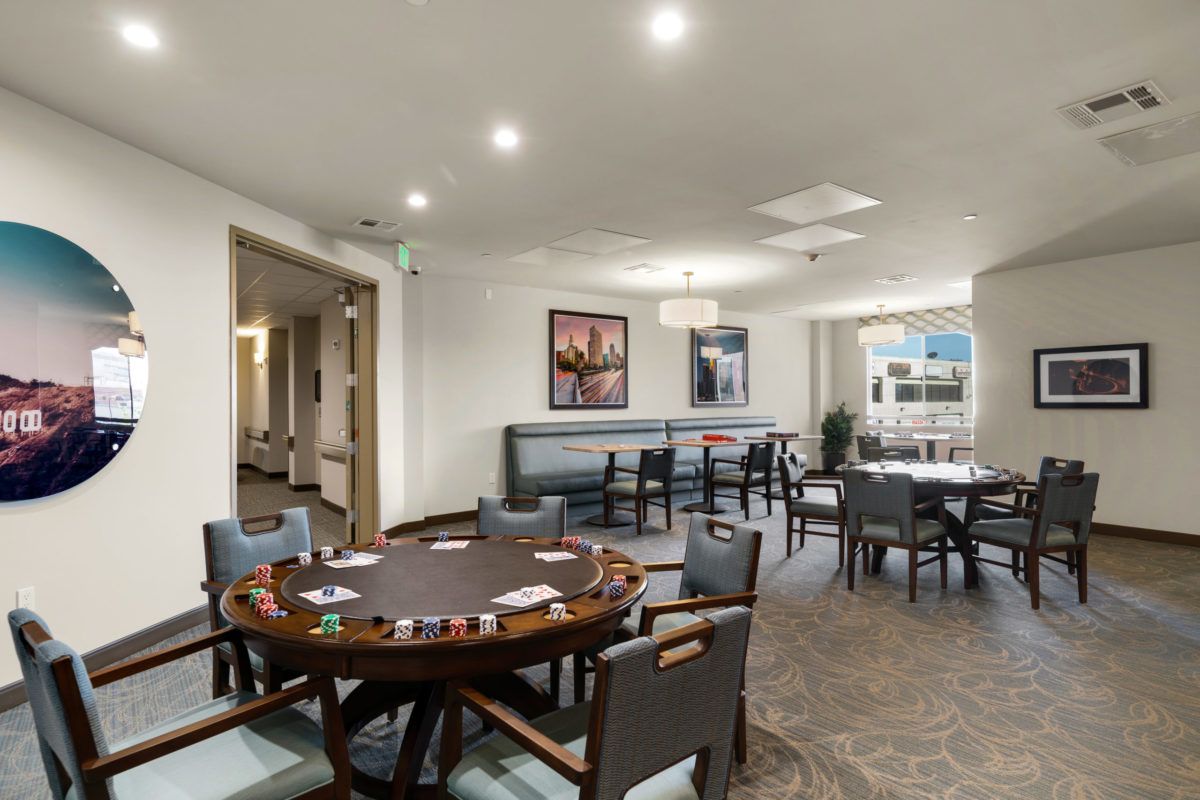 A modern gaming room featuring a poker table with cards and chips, complemented by stylish seating and contemporary decor.
