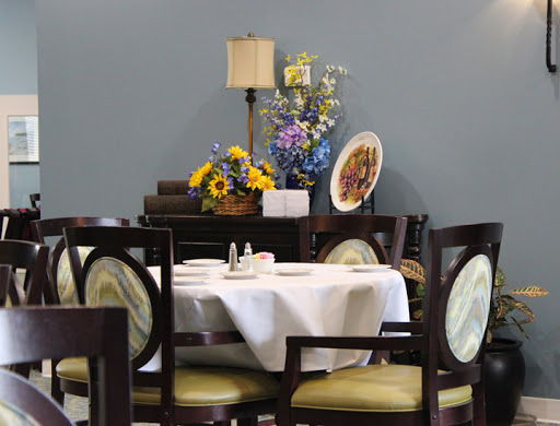 A beautifully arranged dining area featuring a table set for meals, adorned with fresh flowers and elegant decor.