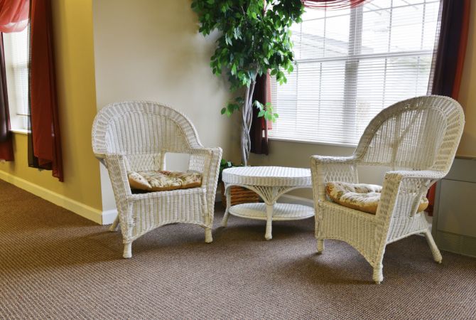 A cozy indoor seating area with wicker chairs and a small table by a window.