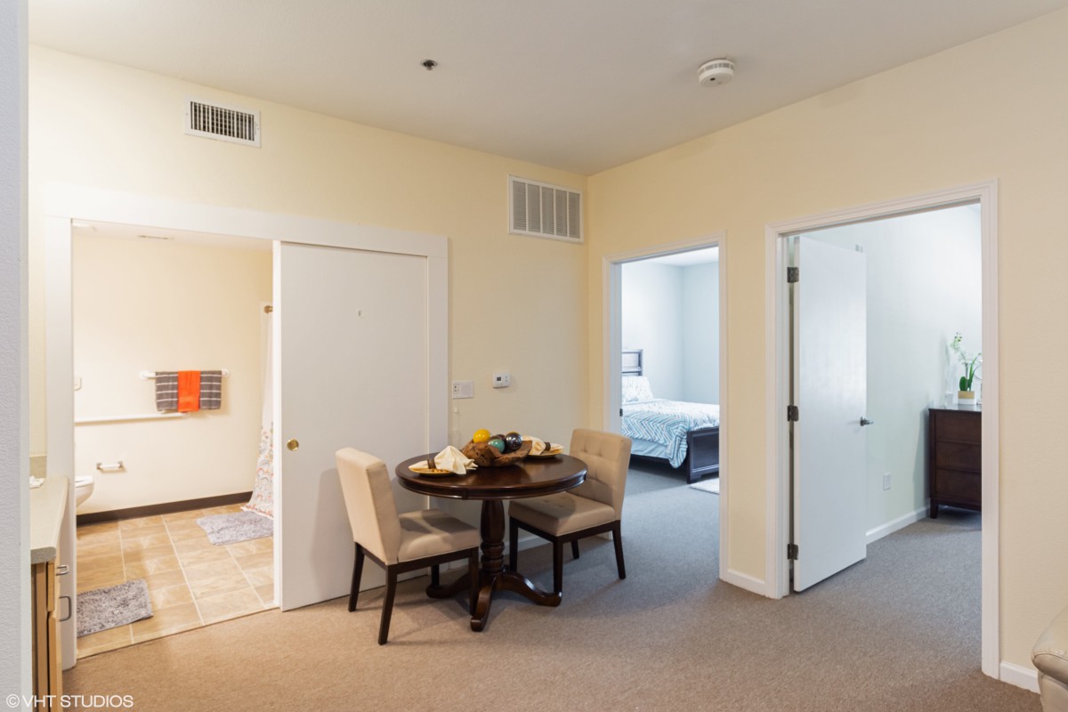 A cozy dining area in an apartment with a view into a bedroom.