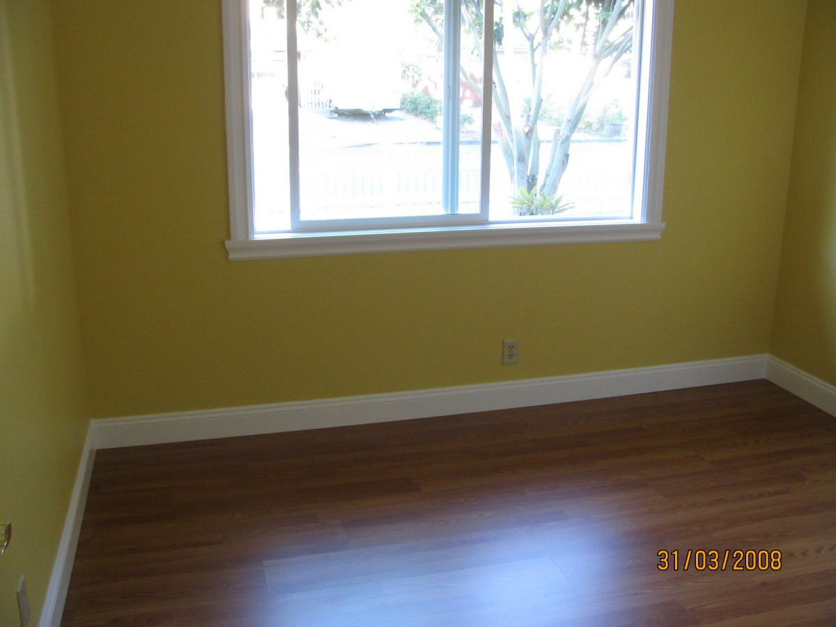 A bright, empty room with yellow walls and a hardwood floor.