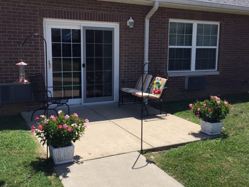 A welcoming outdoor patio area with vibrant flowers and a comfortable bench.