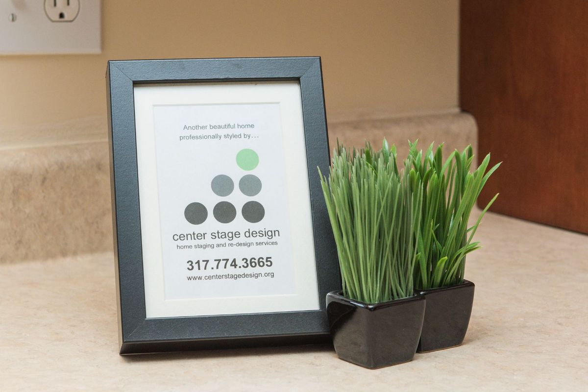 A framed business card displayed alongside a decorative indoor plant.