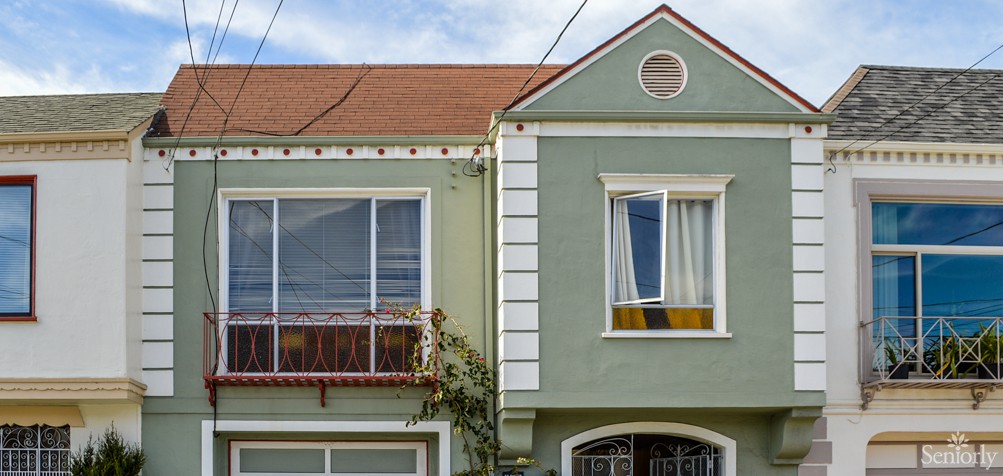 A charming residential house with a green facade and distinctive windows.