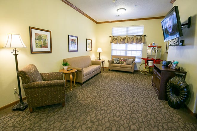 A cozy living room with two sofas, patterned carpet, and a television.