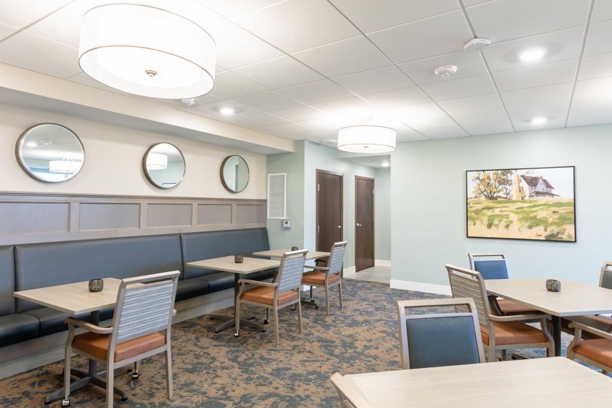 A modern dining area with neatly arranged tables and chairs, featuring contemporary lighting and decor.