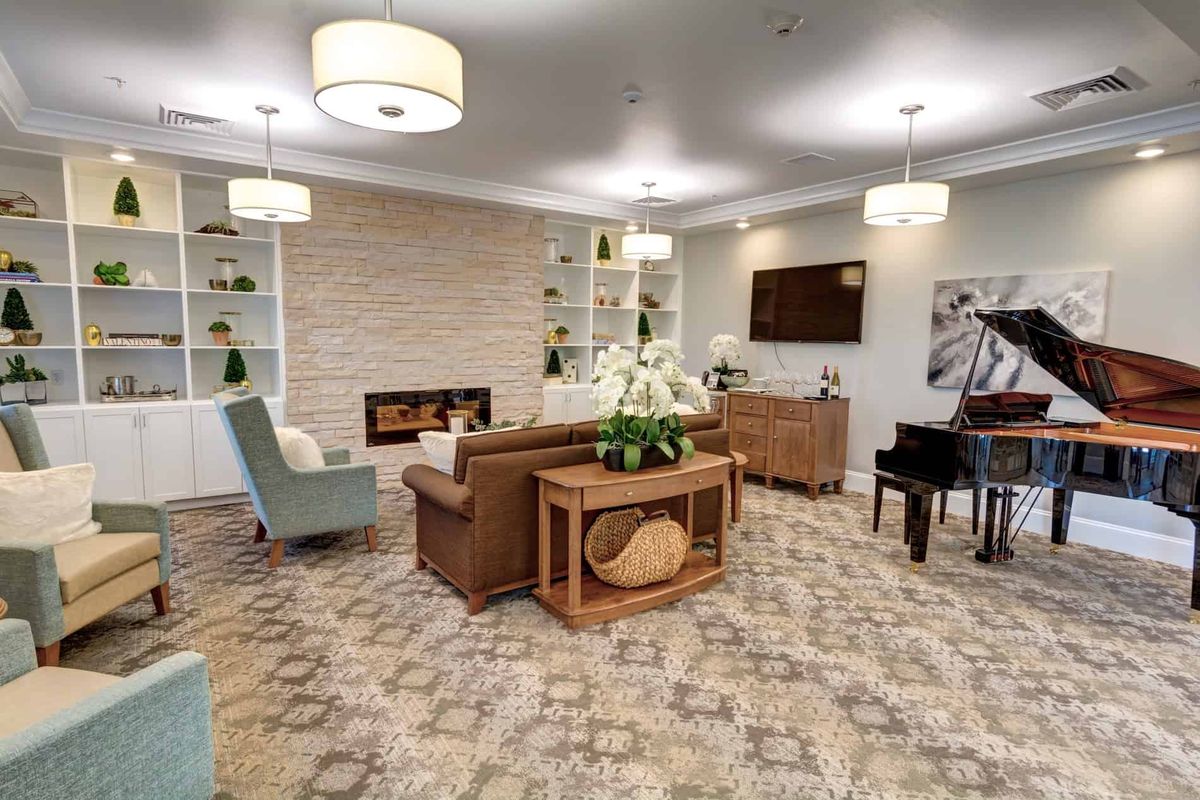 A cozy and modern living room featuring a fireplace, comfortable seating, and a grand piano.