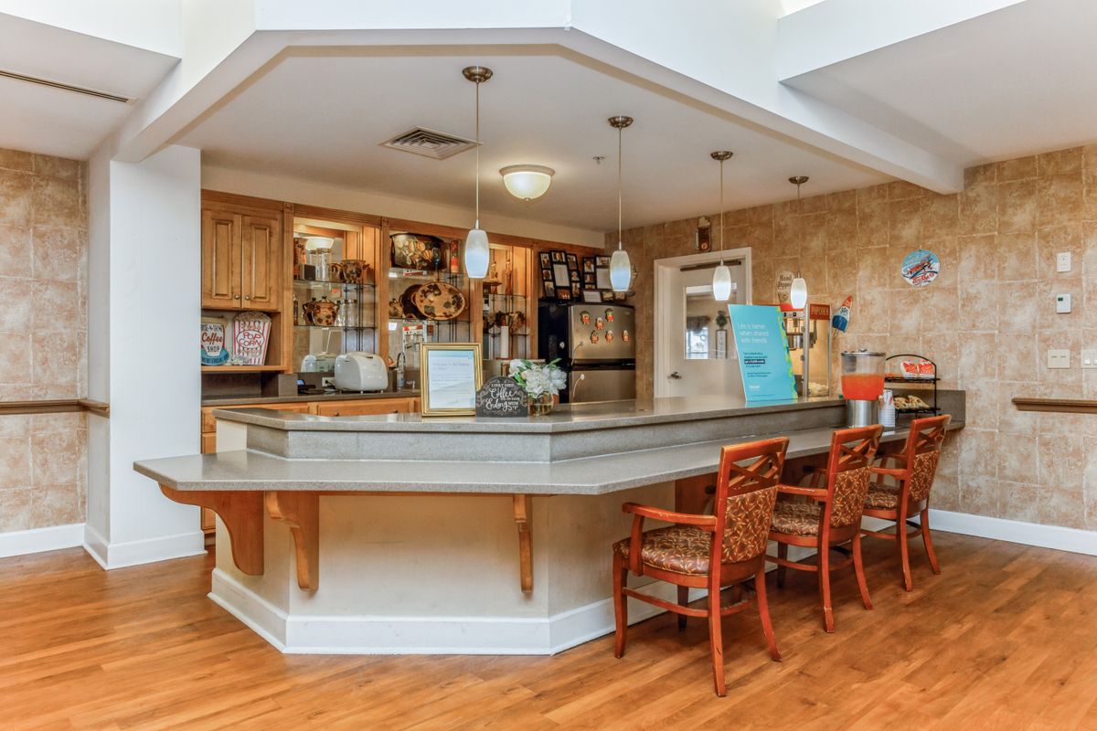 A cozy bar area with a wooden counter and seating, featuring warm lighting and inviting decor.