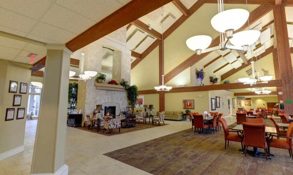 A spacious lobby with a high ceiling, featuring a cozy fireplace and a dining area.