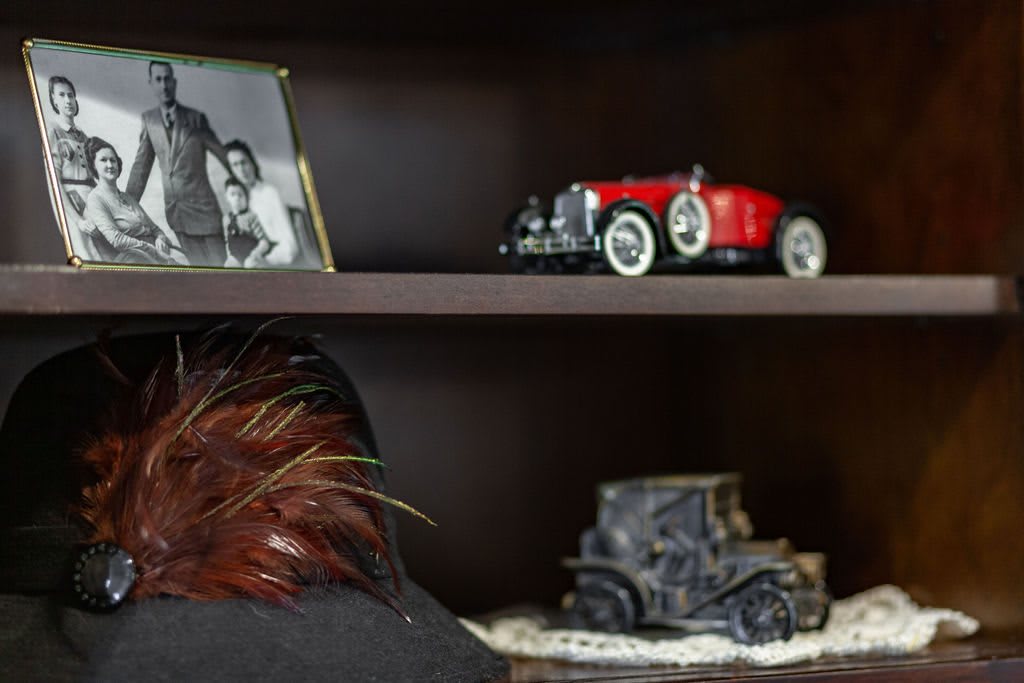 A shelf displaying a model vintage car, a framed photograph, and decorative items.