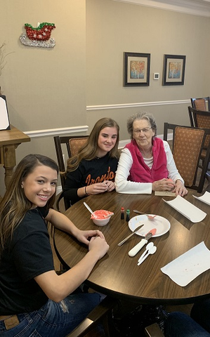 A heartwarming moment shared between two young girls and an elderly woman at a dining table.