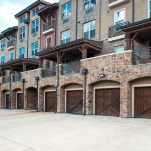 A modern apartment building featuring stone facades and multiple garage doors.
