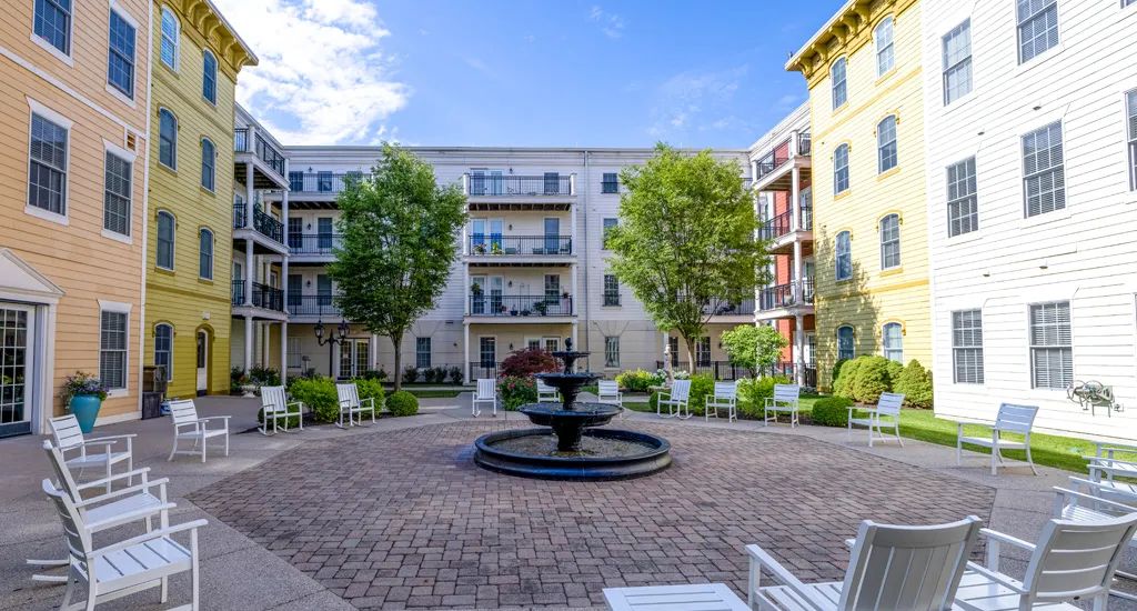 A peaceful courtyard with a central fountain surrounded by apartment buildings and greenery.
