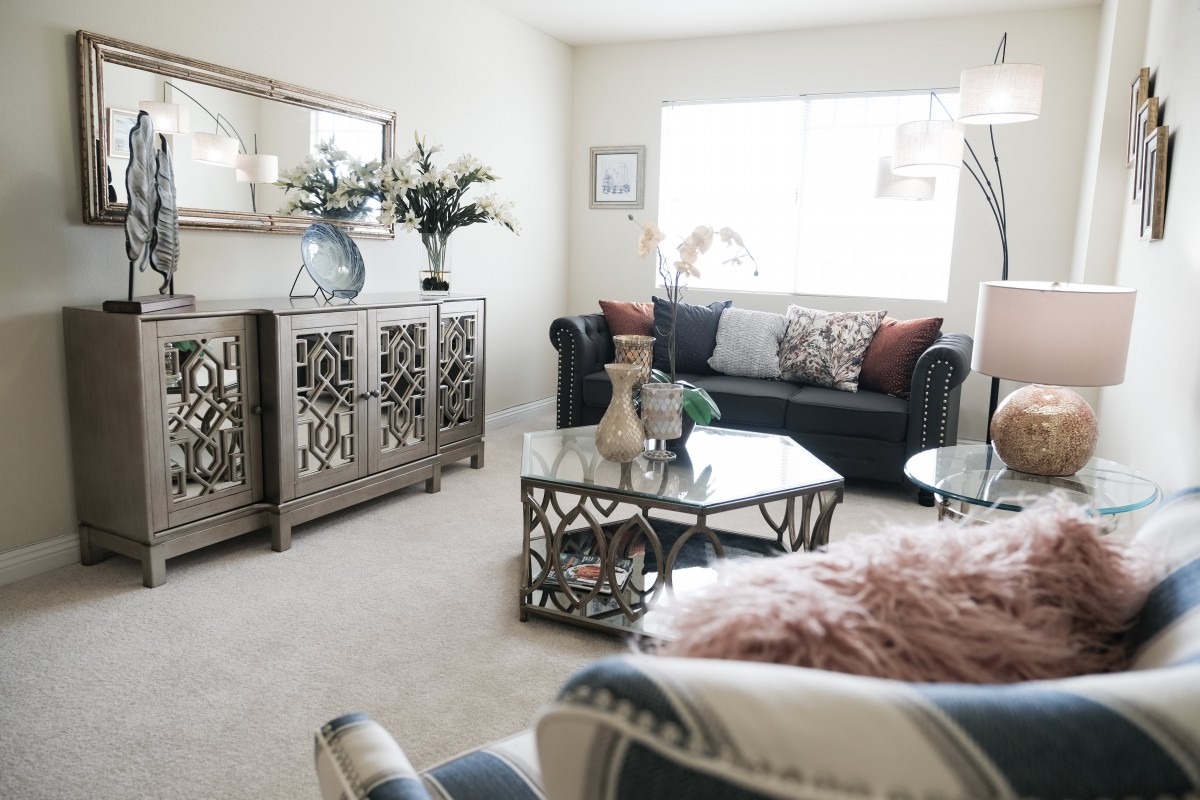 A stylishly decorated living room featuring a sofa, coffee table, and mirrored furniture with elegant decor.