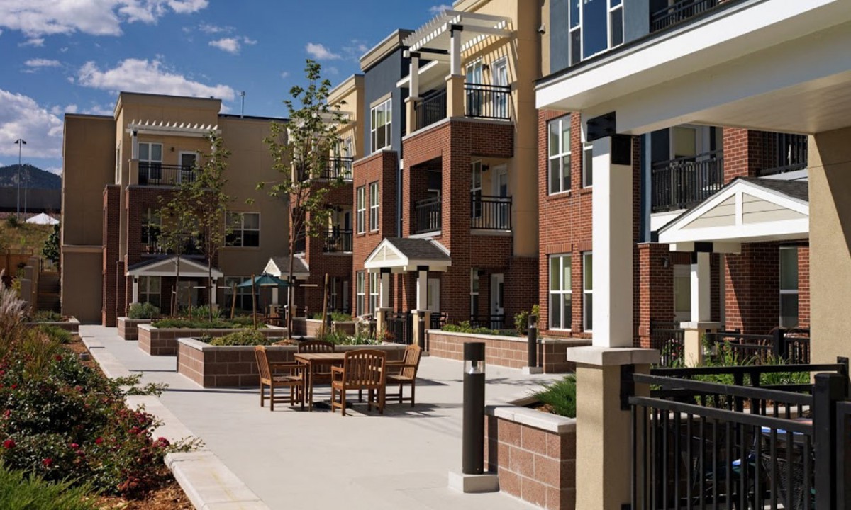 A modern apartment complex with outdoor seating and landscaped areas.