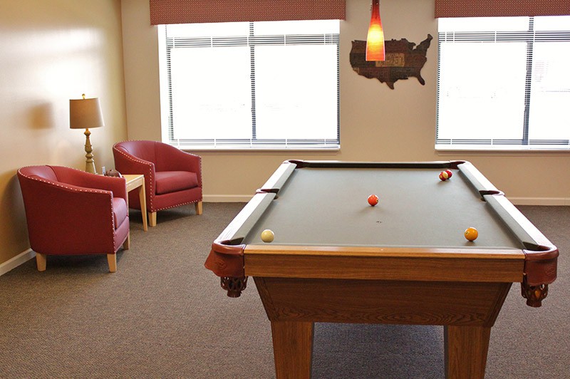 A cozy game room with a pool table and comfortable seating.