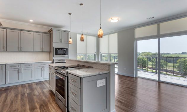 A modern kitchen with an open layout, featuring pendant lighting and hardwood floors.