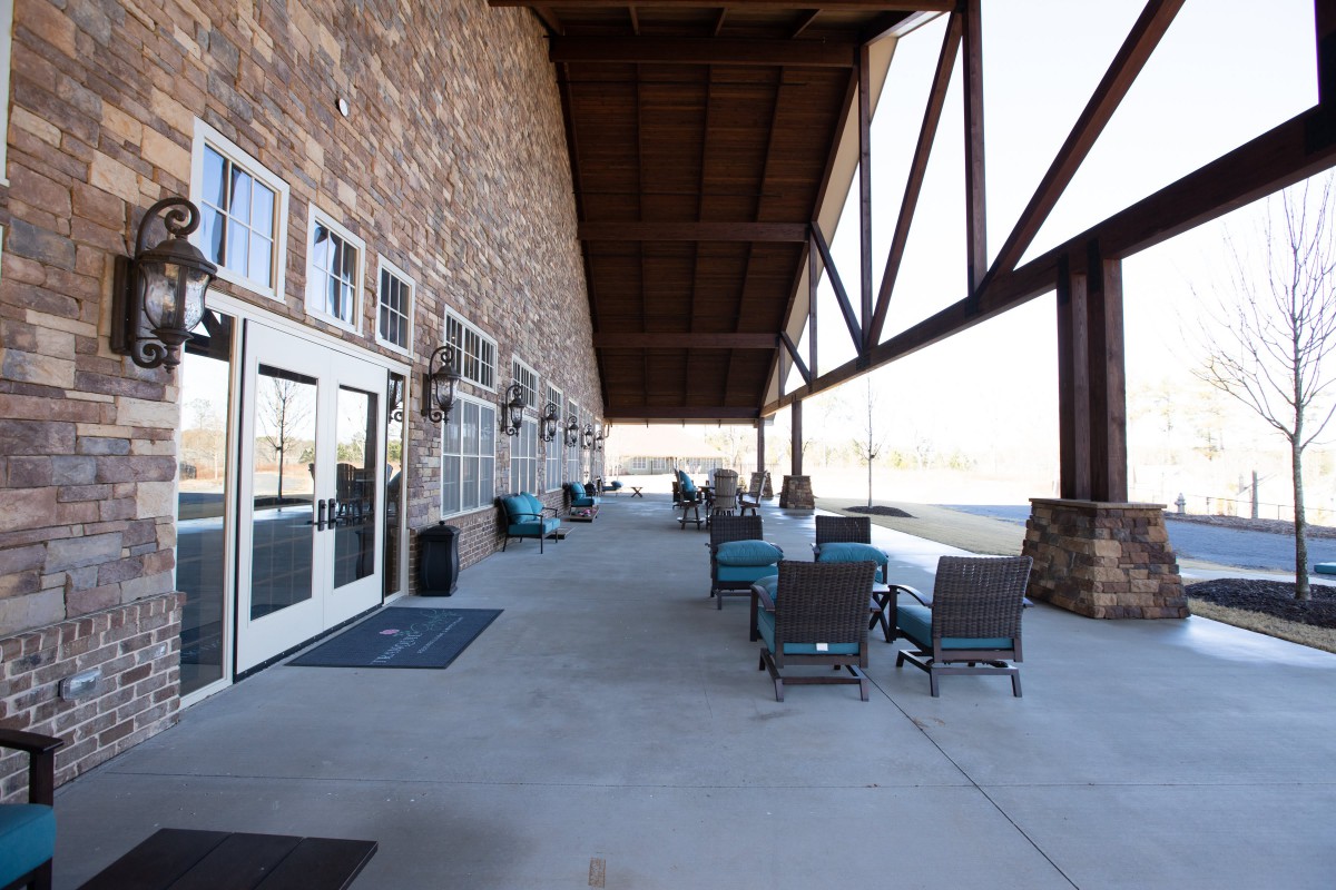 A spacious outdoor patio with seating and a stone wall under a large veranda.