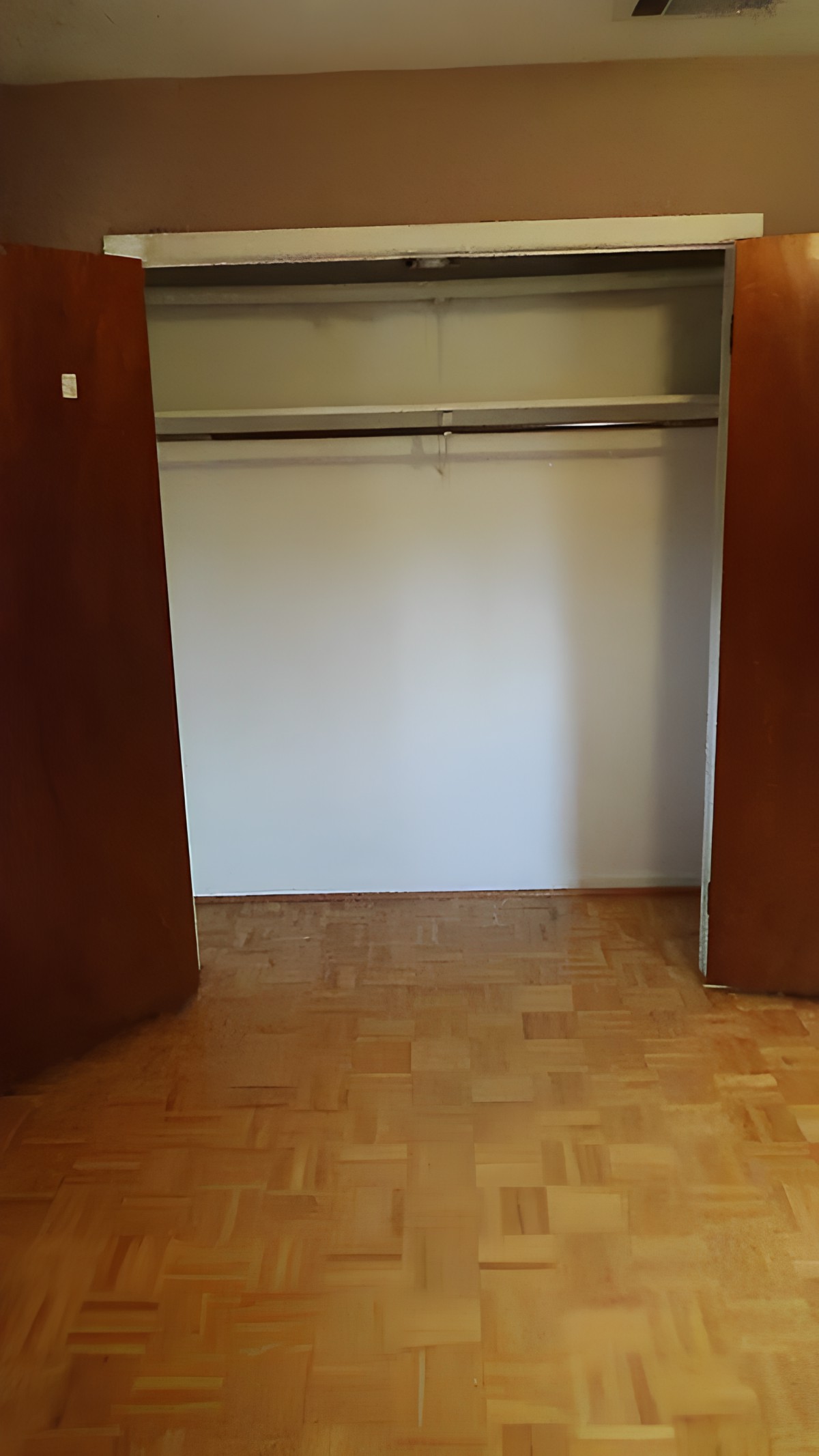 An empty closet with open wooden doors and a hanger rod inside.