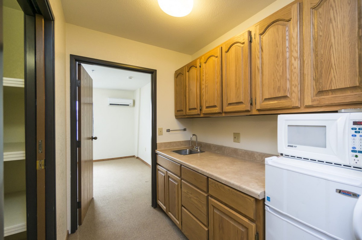 A compact kitchen with wooden cabinets and essential appliances.