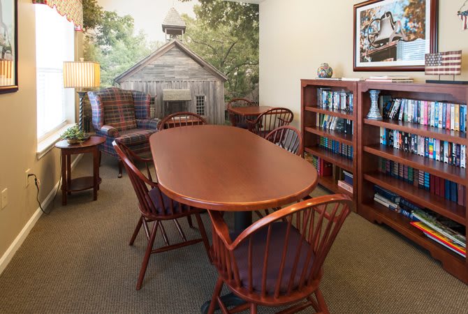 A cozy conference room with a wooden table, chairs, and a decorative mural on the wall.