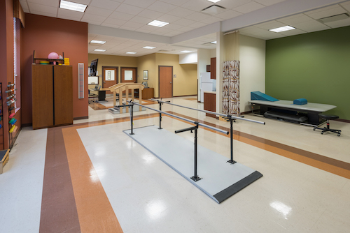 Inside view of a rehabilitation therapy room featuring walking bars for patient assistance.