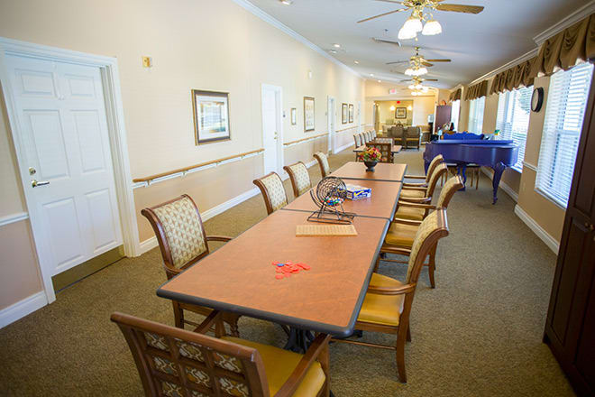 A well-lit conference room featuring a long table surrounded by chairs, with ceiling fans and wall decorations.