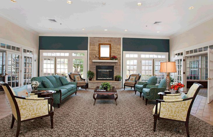 A modern living room with multiple seating arrangements, featuring a central fireplace and elegant furniture.