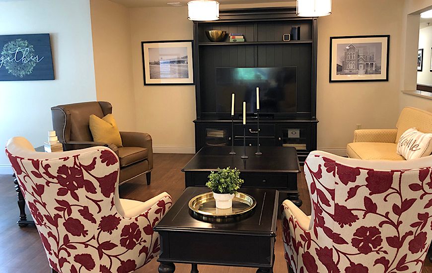 A cozy and modern living room with patterned armchairs, a central coffee table, and an entertainment unit with a television.
