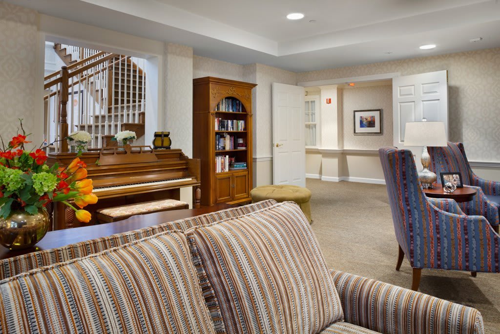 A cozy living room with a piano and a bookshelf as focal points.
