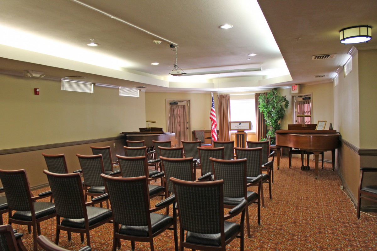 An empty meeting room with chairs arranged in rows and an American flag in the corner.