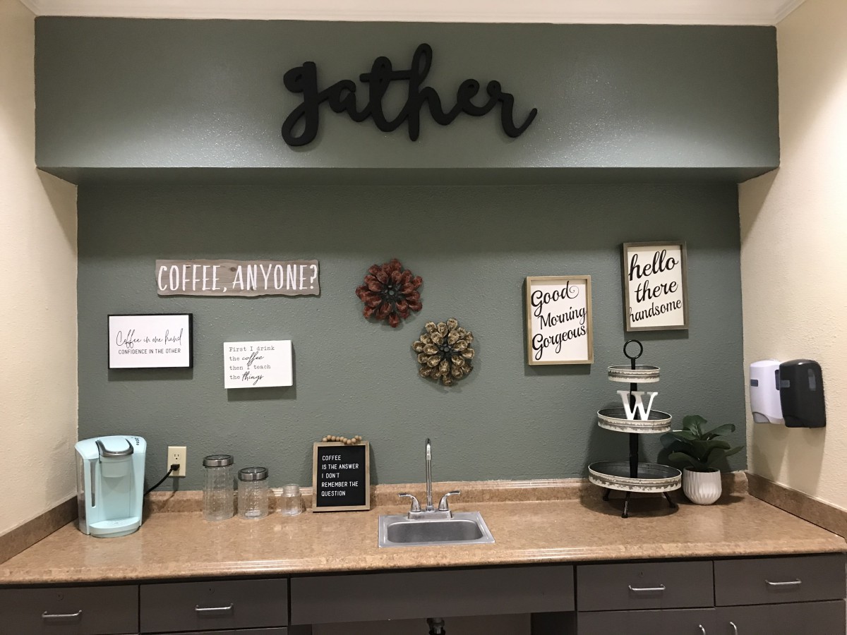 A cozy kitchenette setup with motivational signs and a coffee station.