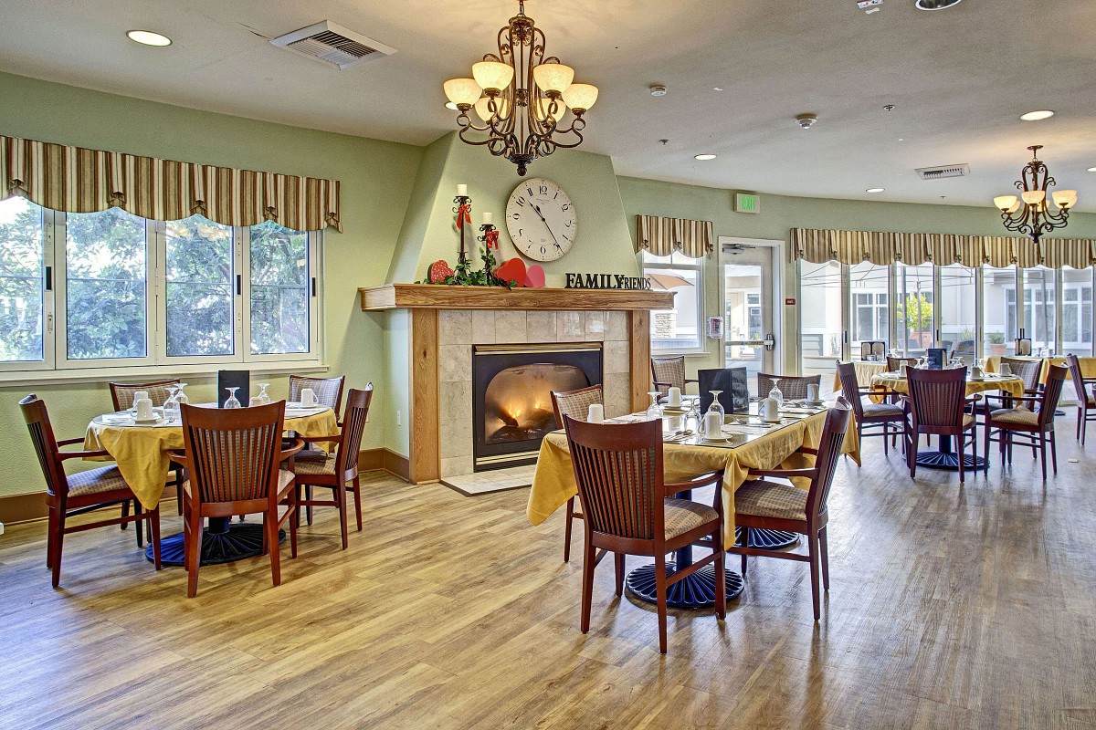 A cozy dining room with elegant decor, featuring a fireplace and chandelier.