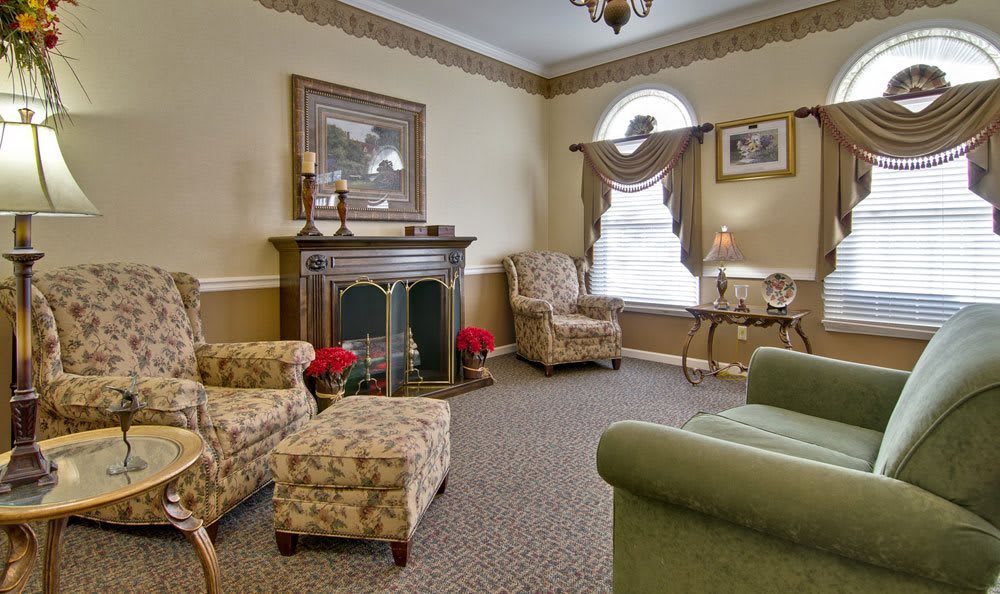 A cozy living room with classic decor, featuring armchairs, a fireplace, and elegant furnishings.