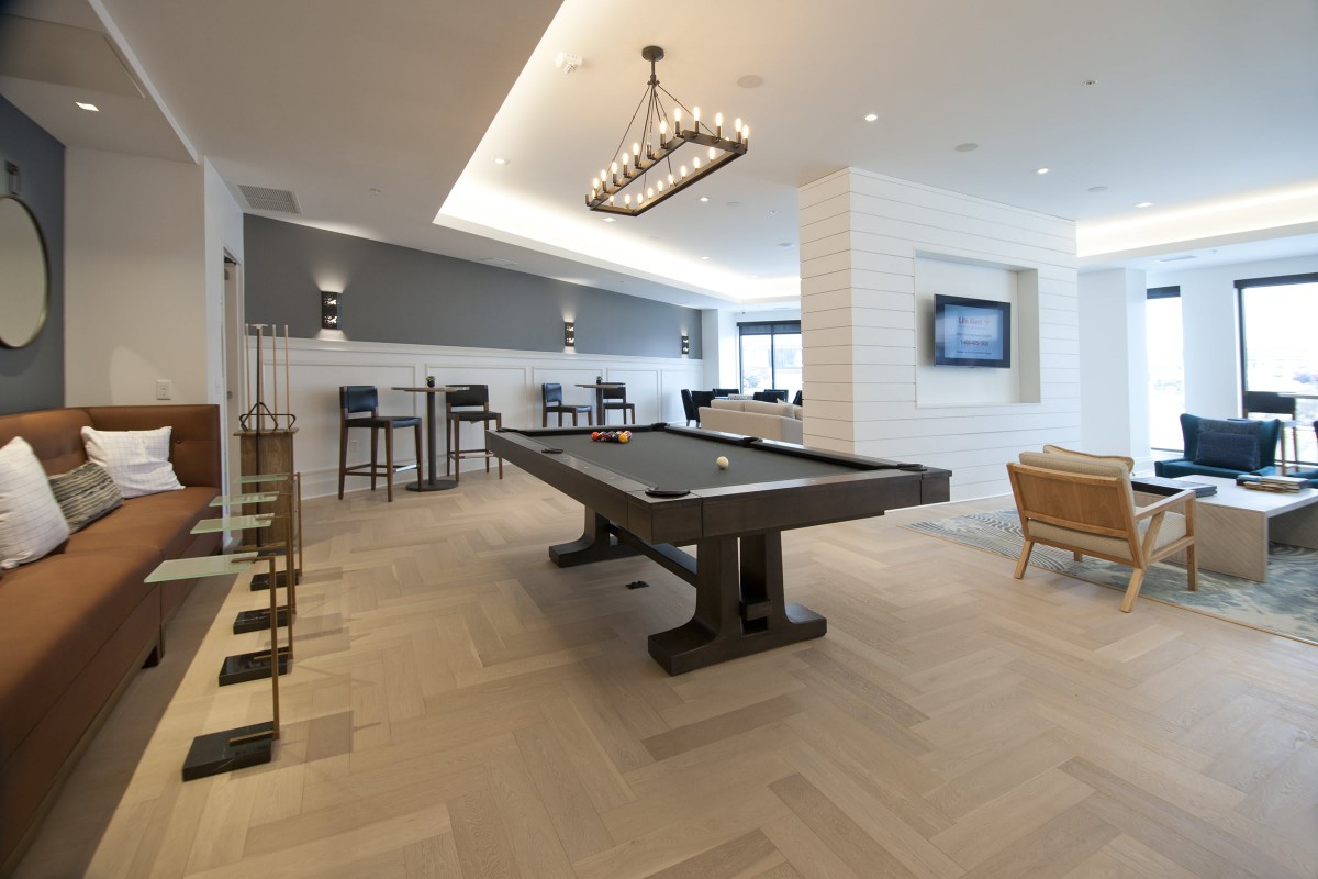 Modern recreational room featuring a pool table and bar seating.
