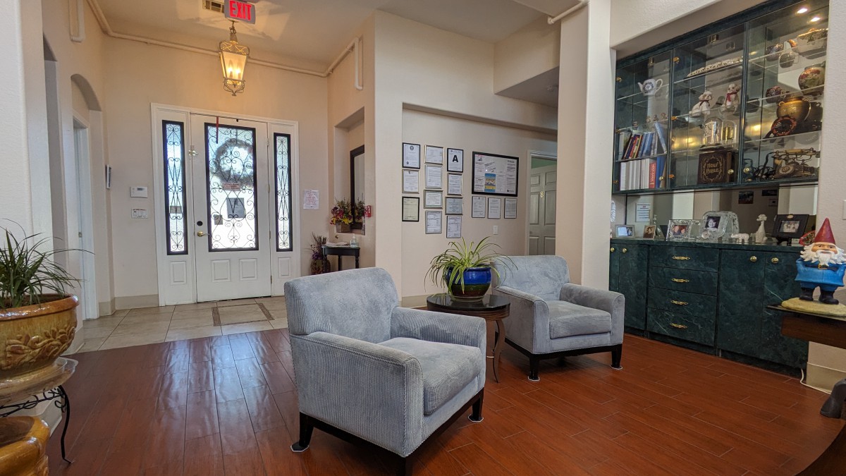 A cozy living room featuring two upholstered chairs, wooden flooring, and decorative elements on the walls and shelves.