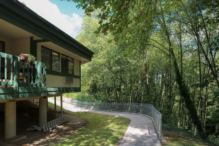 A house with a pathway leading into a lush forest area.