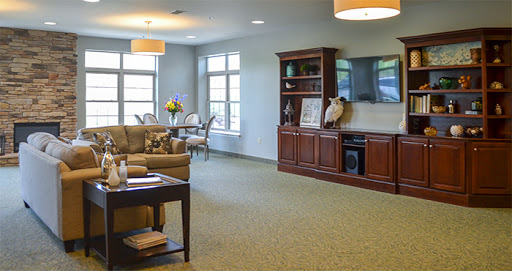 A cozy living room featuring comfortable seating, a television unit, and natural light filtering through large windows.